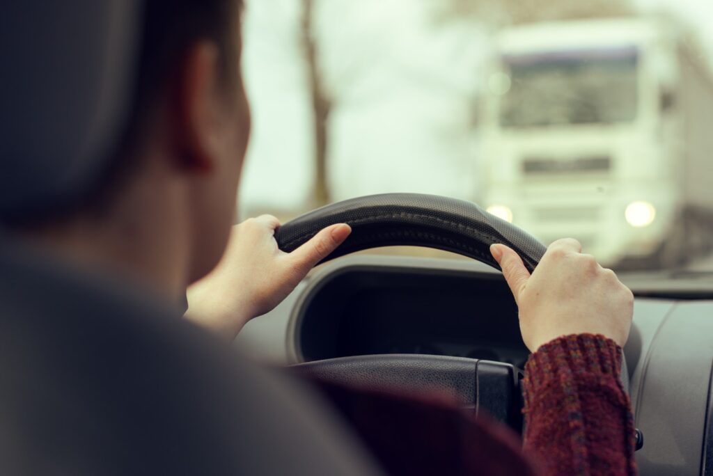 $350,000 Settlement With Farm Bureau And Shelter Insurance | Cantor Injury Law Woman driving car toward a large truck on the road. Settlement With Farm Bureau And Shelter Insurance.